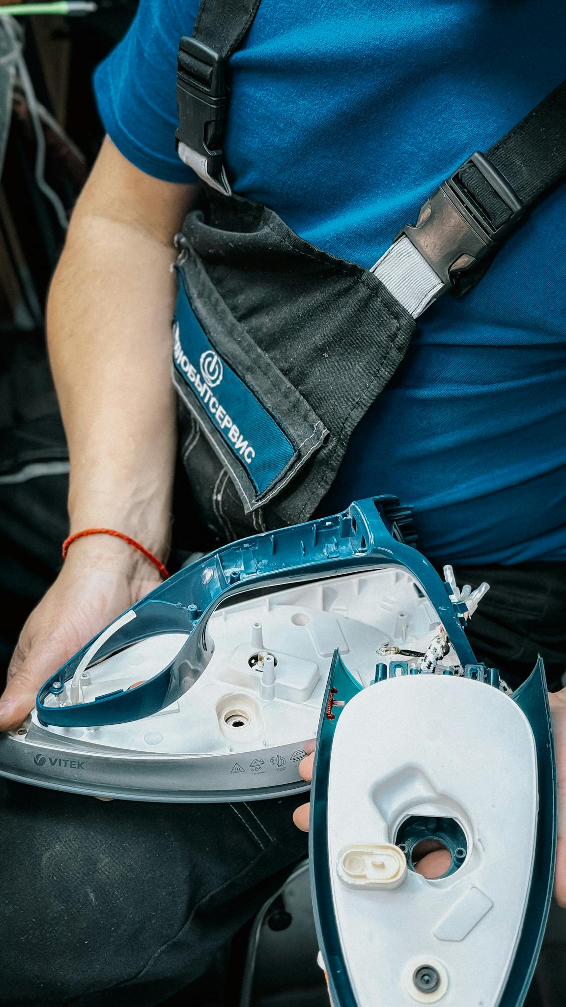 Close-up of technician disassembling an iron for repair.
