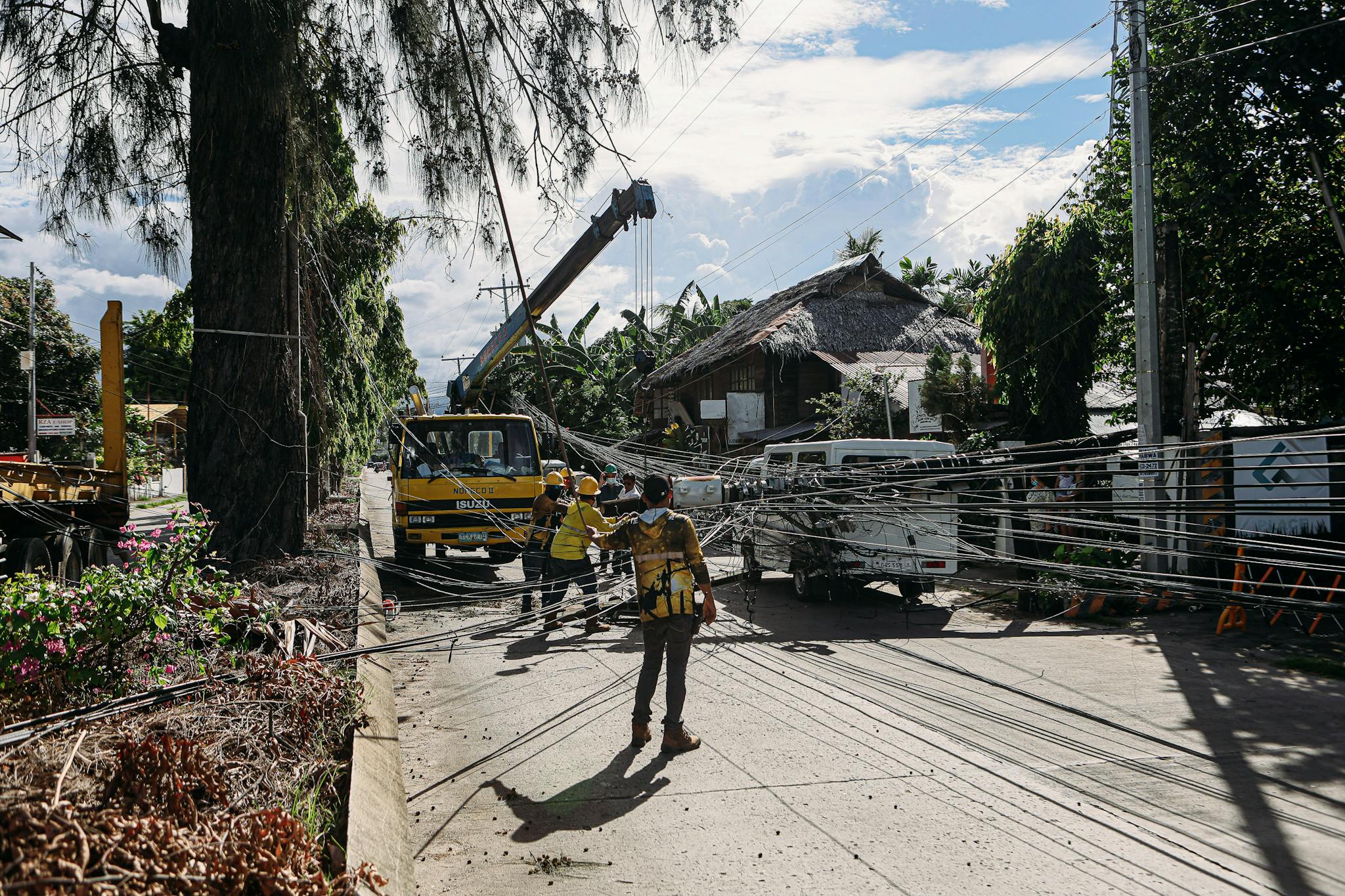 Utility workers fixing downed power lines in a tropical area after a storm. Essential infrastructure maintenance.