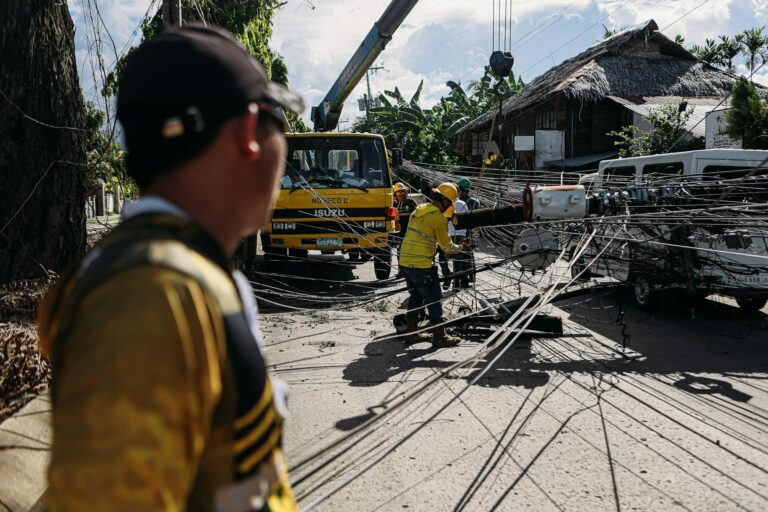 Utility workers assess and fix downed power lines on a sunny day, ensuring safety and service restoration.